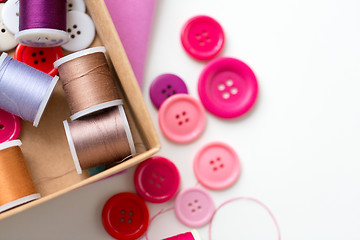 Image showing box with thread spools and sewing buttons on table