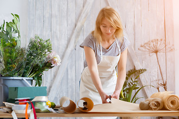 Image showing Florist girl cuts wrapping paper