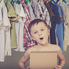 Image showing portrait of a little boy standing near a hanger with clothes