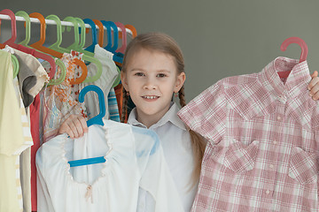 Image showing portrait of a little girl standing near a hanger with clothes