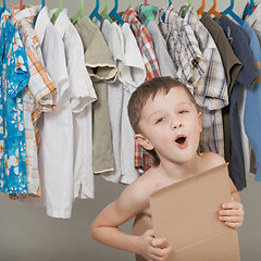 Image showing portrait of a little boy standing near a hanger with clothes