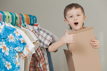 Image showing portrait of a little boy standing near a hanger with clothes