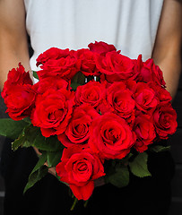 Image showing Male person holding a beautiful bouquet of red roses wearing whi