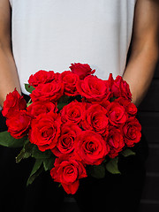 Image showing Male person holding a beautiful bouquet of red roses wearing whi