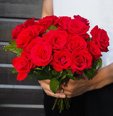 Image showing Male person holding a beautiful bouquet of red roses wearing whi