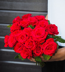 Image showing Male person holding a beautiful bouquet of red roses wearing whi