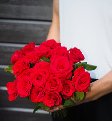 Image showing Male person holding a beautiful bouquet of red roses wearing whi