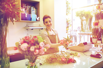 Image showing smiling florist woman making bunch at flower shop