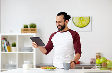 Image showing man with tablet pc eating at home kitchen