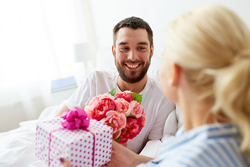 Image showing happy couple with gift box in bed at home