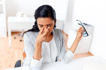 Image showing businesswoman rubbing tired eyes at office