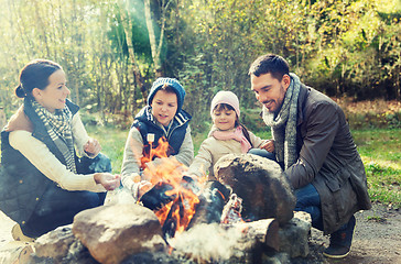 Image showing happy family roasting marshmallow over campfire