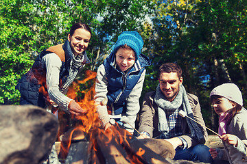 Image showing happy family roasting marshmallow over campfire