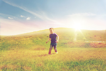 Image showing happy little boy running on green field outdoors