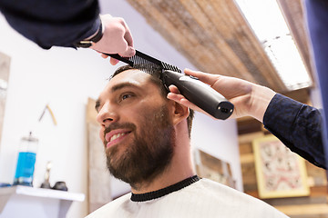 Image showing man and barber with trimmer cutting hair at salon