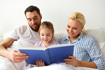 Image showing happy family reading book in bed at home