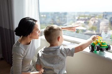 Image showing mother and son looking through window at home