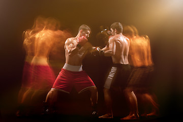 Image showing The two male boxers boxing in a dark studio