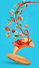 Image showing Tasty pizza and falling ingredients on blue background