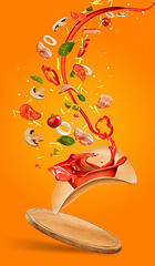 Image showing Tasty pizza and falling ingredients on orange background