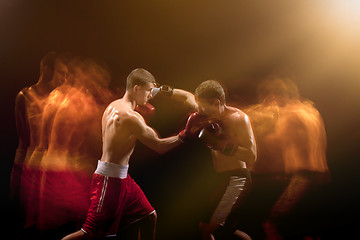 Image showing The two male boxers boxing in a dark studio