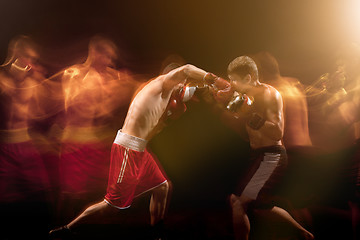 Image showing The two male boxers boxing in a dark studio