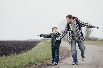 Image showing Father and son walking on the road at the day time.