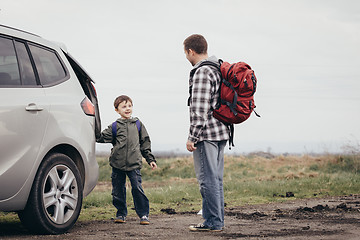 Image showing Father and son walking on the road at the day time.