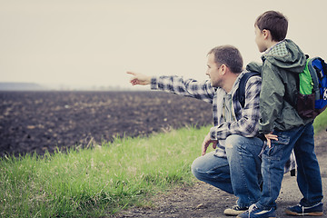 Image showing Father and son walking on the road at the day time.