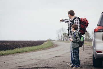 Image showing Father and son walking on the road at the day time.