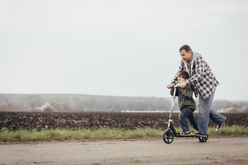 Image showing Father and son walking on the road at the day time.