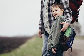 Image showing Father and son walking on the road at the day time.