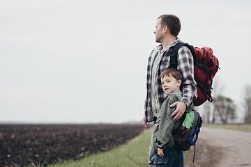 Image showing Father and son walking on the road at the day time.