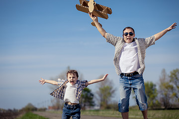 Image showing Father and son playing with cardboard toy airplane in the park a