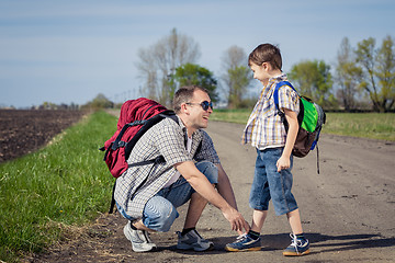 Image showing Father and son walking on the road at the day time.