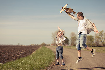 Image showing Father and son playing with cardboard toy airplane in the park a