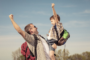 Image showing Father and son walking on the road at the day time.