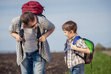 Image showing Father and son walking on the road at the day time.