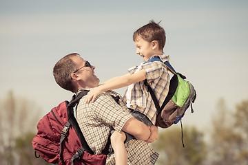 Image showing Father and son walking on the road at the day time.