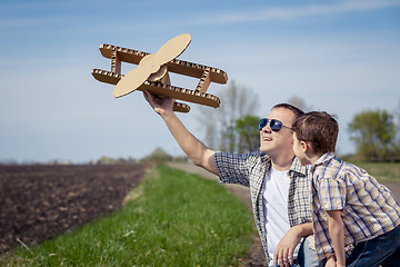 Image showing Father and son playing with cardboard toy airplane in the park a