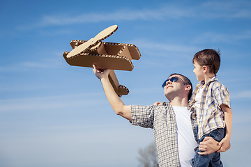 Image showing Father and son playing with cardboard toy airplane in the park a