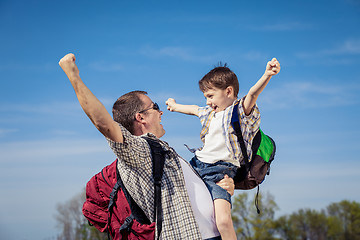 Image showing Father and son walking on the road at the day time.