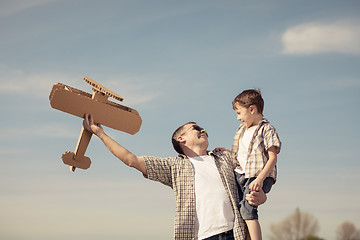 Image showing Father and son playing with cardboard toy airplane in the park a