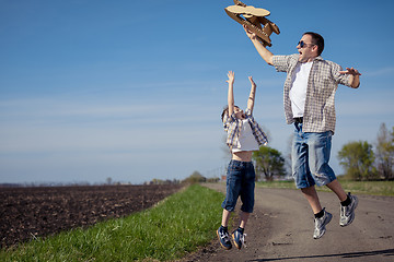 Image showing Father and son playing with cardboard toy airplane in the park a