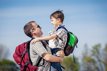 Image showing Father and son walking on the road at the day time.