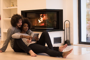 Image showing multiethnic couple using tablet computer on the floor