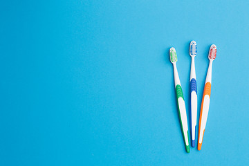 Image showing Three toothbrushes on blue background