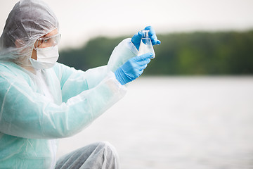 Image showing Chemist looks at water flask