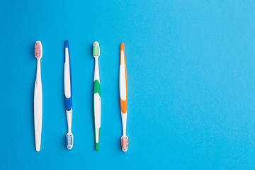 Image showing Multi-colored toothbrushes on blue background