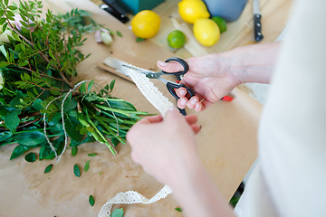 Image showing Florist cuts ribbon for bouquet